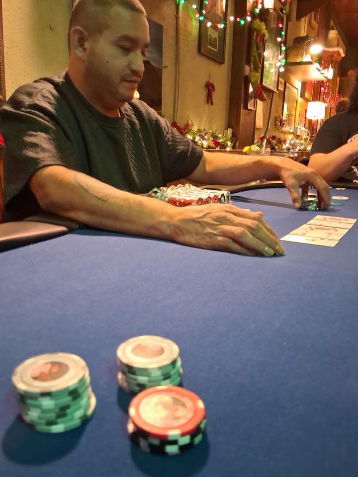 The dealer dealing cards at a poker table, chip rack in front